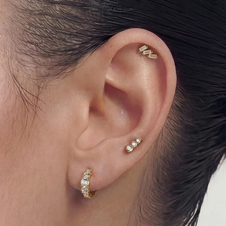 Model wearing the 14K yellow gold baguette lab grown diamond three-stone stud earrings in a styled ear stack | AJ's Jewelry