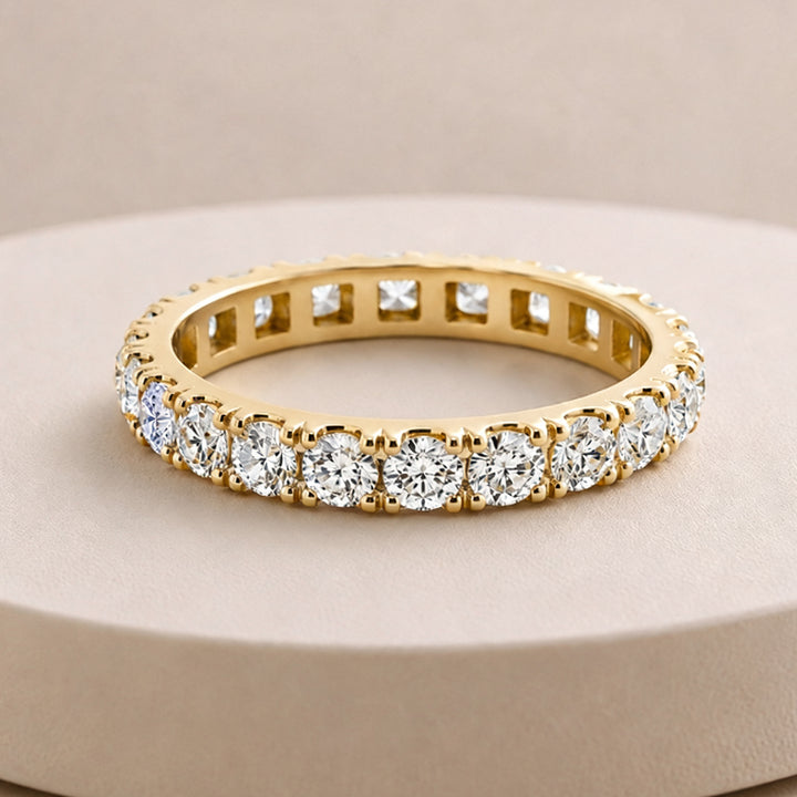 14 karat yellow gold lab grown diamond eternity band shown from the front on a styled display at AJ's Jewelry in Ridgewood, Queens NY