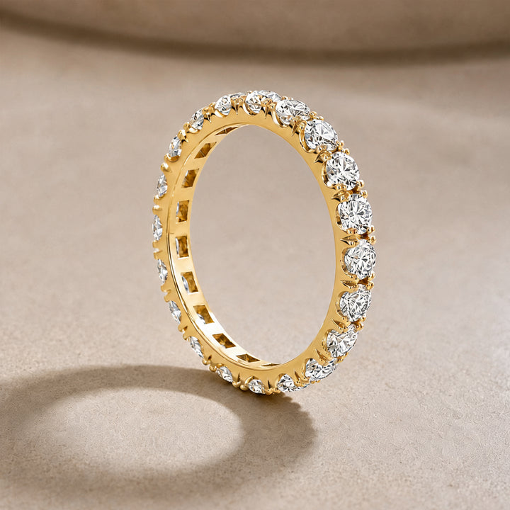 14 karat yellow gold lab grown diamond eternity band shown from the side on a styled display at AJ's Jewelry in Ridgewood, Queens NY
