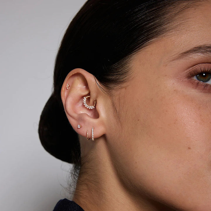 Model wearing the 14K yellow gold natural diamond curved cluster flat back stud earrings in a styled ear stack | AJ's Jewelry