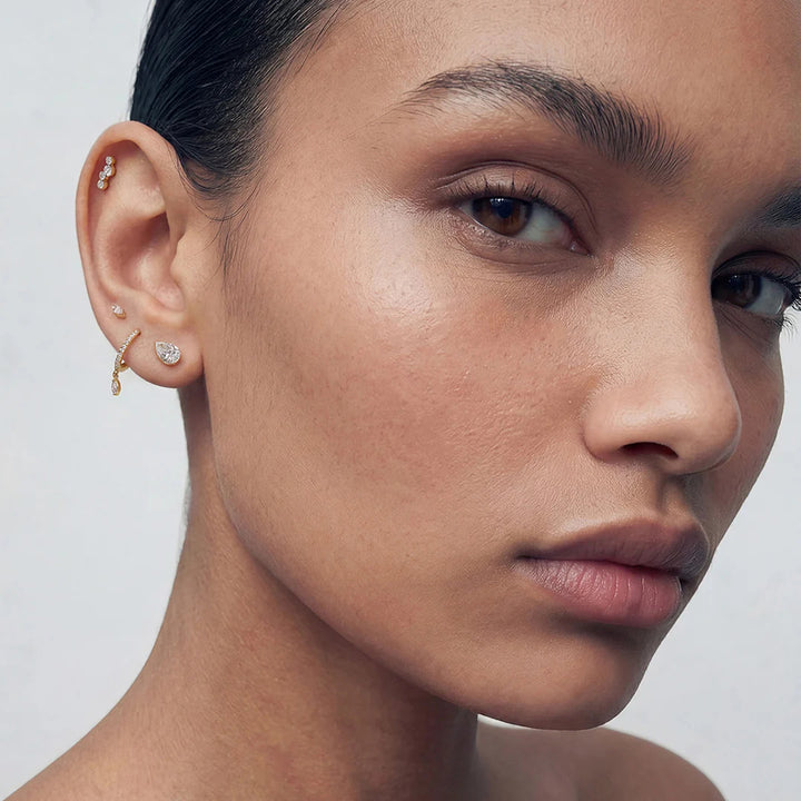Model wearing the 14K yellow gold pear lab grown diamond flat back stud earrings in a styled ear stack | AJ's Jewelry
