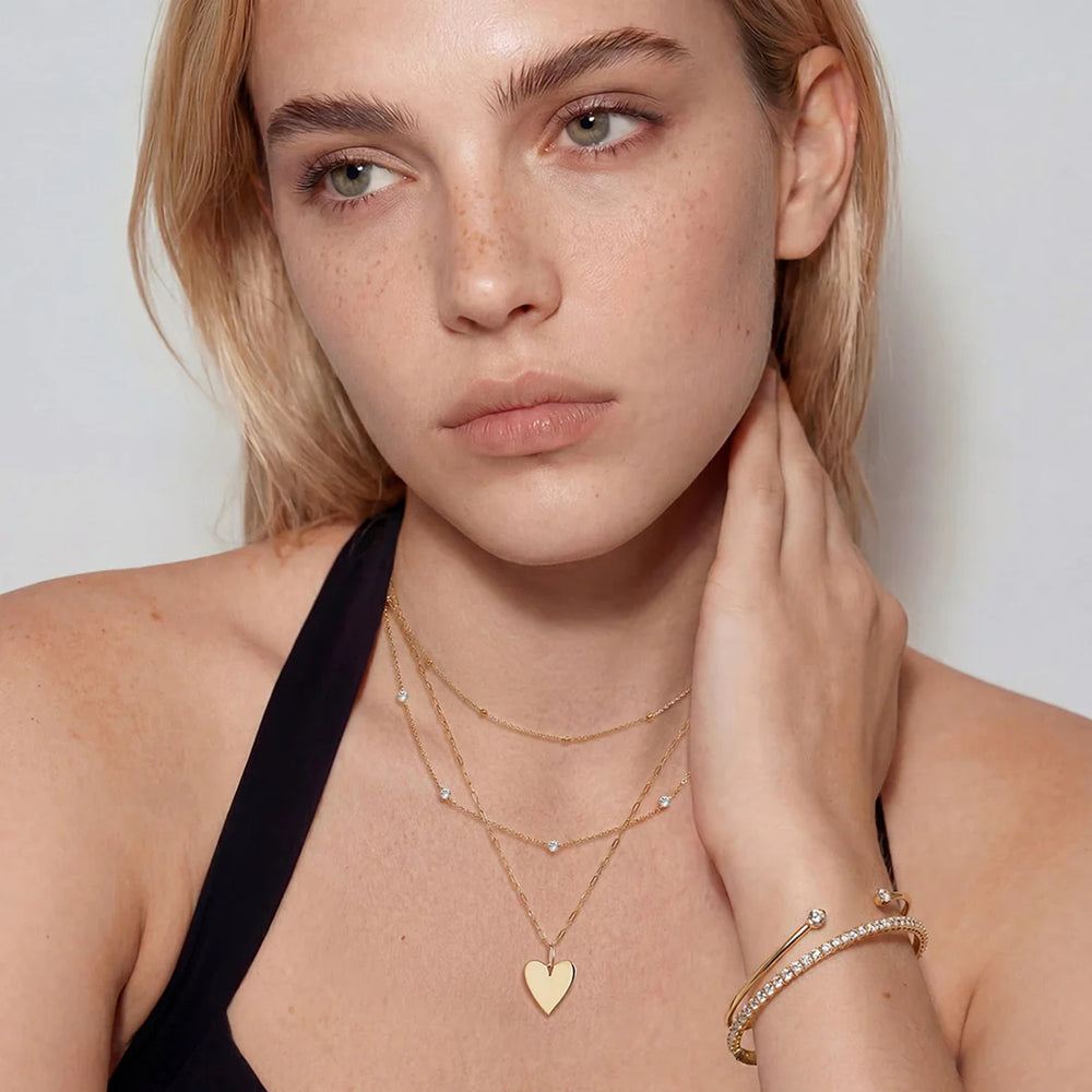 Model wearing the 14K yellow gold polished heart pendant necklace layered with other gold necklaces | AJ's Jewelry