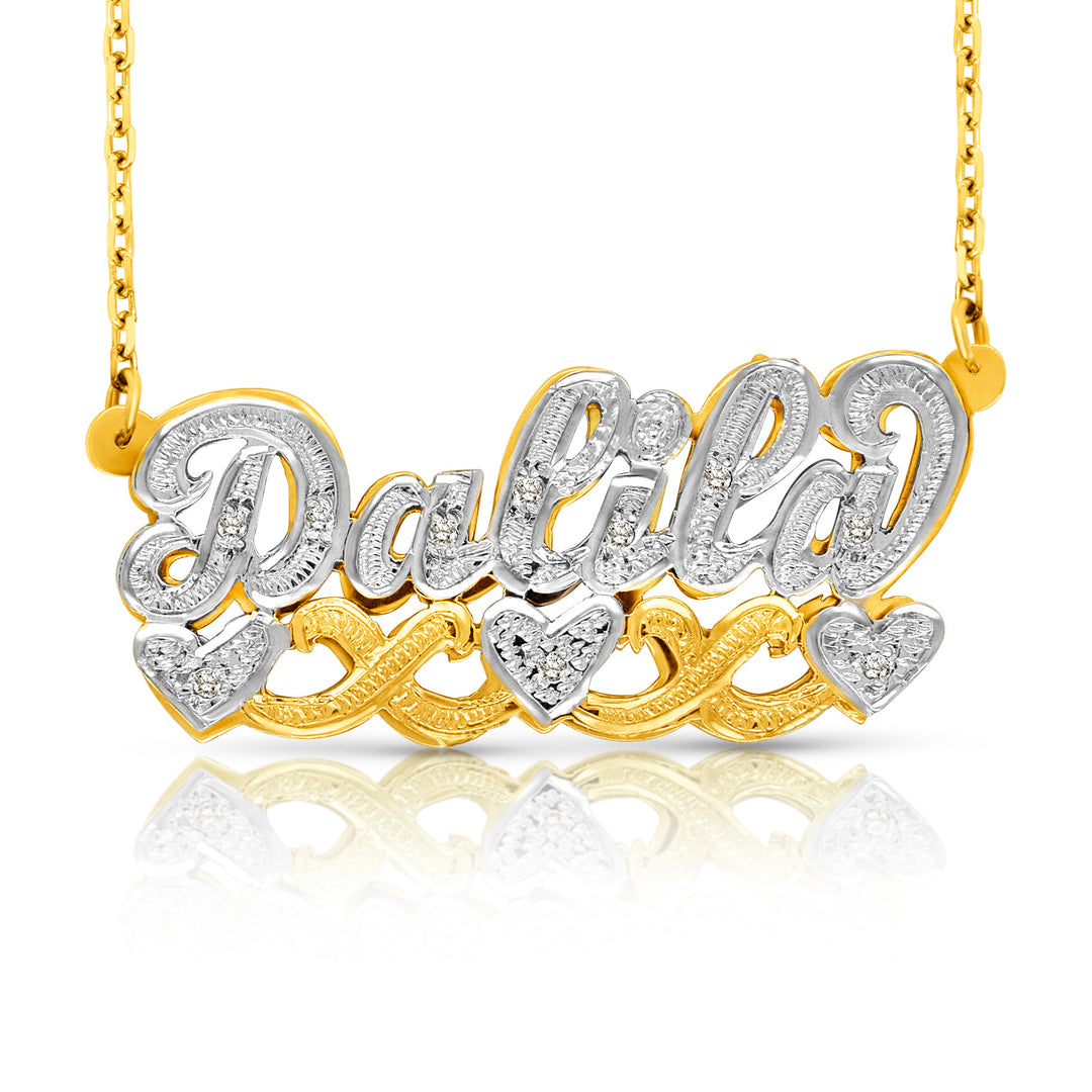 A custom name necklace featuring the name 'Dalia' in cursive script, embellished with small clear stones, with three heart-shaped accents. The necklace is made of yellow gold and white gold, suspended from a gold chain against a white background with a soft reflection below.