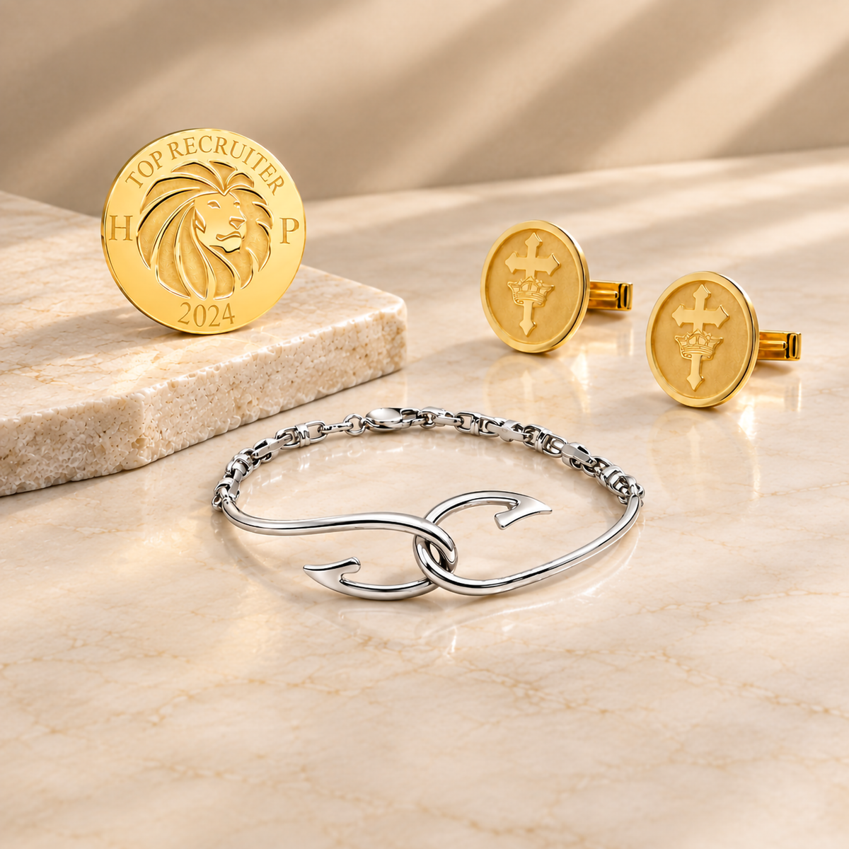 A image showing some of the custom bracelets and accessories done by AJ's Jewelry, including a corporate lapel pin, fish hook bracelet, and gold plated cufflinks on a luxury themed background