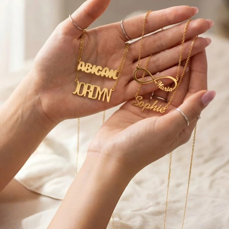 Custom gold name necklaces held in a hand 