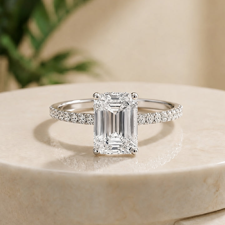 Custom 14KT white gold hidden halo emerald-shape lab-grown diamond engagement ring shown from the front on a styled display at AJ's Jewelry in Ridgewood, Queens NY