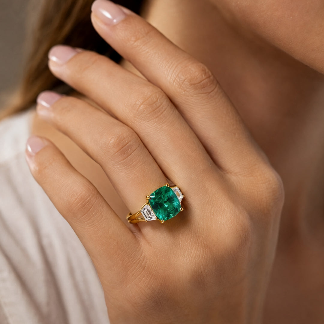 Custom 14KT yellow gold lab-grown emerald three-stone ring worn on a hand at AJ's Jewelry in Ridgewood, Queens NY