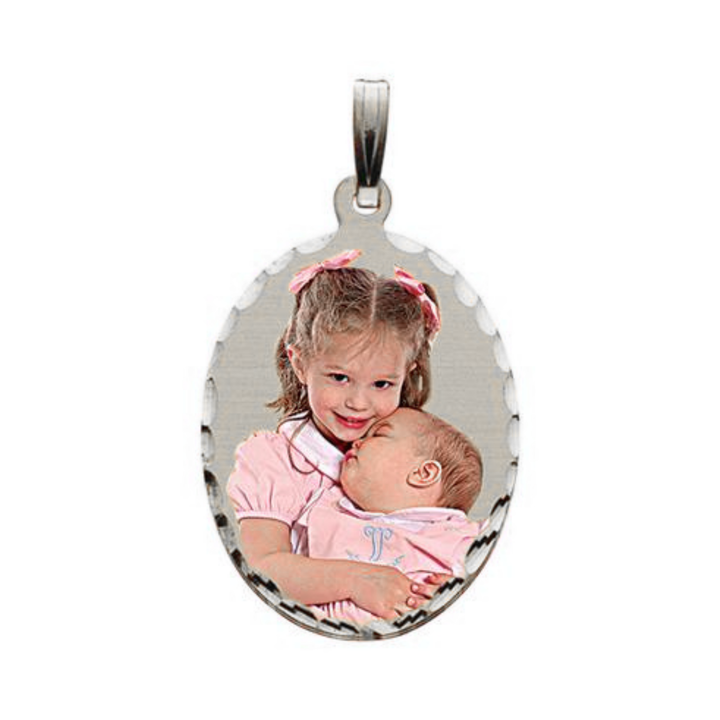 A silver oval shaped pendant with a custom photo of a young girl holding a baby, shown on a plain white background.